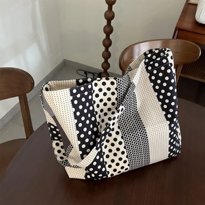 Dettaglio della borsa tote in tela a pois bianchi e neri su un tavolo di legno rustico