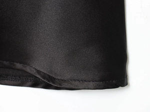 Détail de couture de l'ourlet sur une robe en satin noir avec texture et éclat soyeux