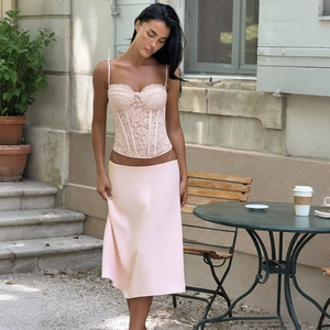 Détail du haut corset en dentelle rose clair avec texture délicate et motifs floraux