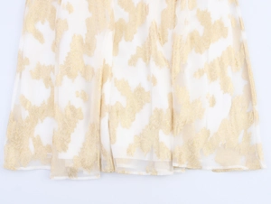 Détail d'une robe sans manches crème montrant la texture jacquard dorée et l'éclat métallique