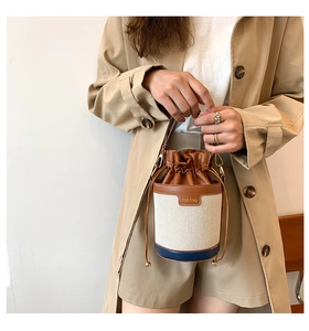 Detail of canvas bucket bag with brown leather trim and drawstring closure mechanism