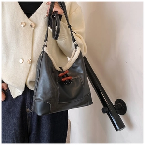 Detail of black leather tote bag with white fleece trim and wooden toggle buttons
