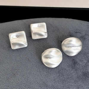 Matte silver geometric textured stud earrings set on grey velvet background
