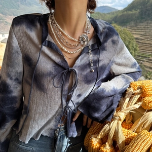 Detail of layered silver chains with pearl beads and lion head pendant on model