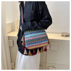Ethnic style shoulder bag with bohemian woven patterns and tassel fringe details on a model