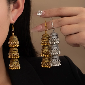 Detailed macro view of three-tier vintage Jhumka earrings with intricate carved hollow patterns