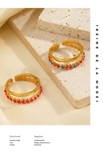 Detail of double-layer gold ring featuring colorful enamel dots on a stone surface