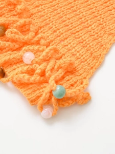 Detailed close-up of orange knit swimwear with colorful decorative beads and tassels