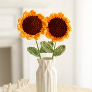 Detailed view of hand-knitted crochet sunflowers in a white geometric ceramic vase