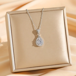 Elegant silver teardrop pendant necklace with sparkling crystals on gold jewelry box