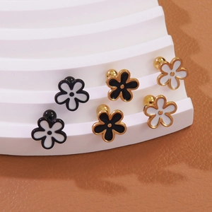 Three pairs of floral titanium steel stud earrings in black, white, and gold finishes