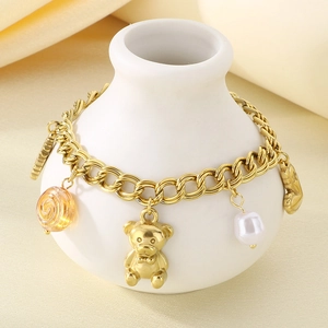 Detail of gold-plated bracelet featuring resin bear, pearl, and colorful charms on ceramic