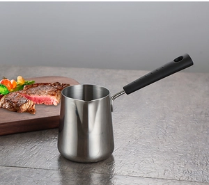 Mini stainless steel butter melting pot with long black handle on a kitchen counter