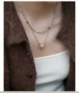 Close-up of double-layer necklace with pearls, brown beads and sparkling zircon pendant