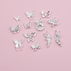 Set of 12 silver alloy butterfly nail charms with rhinestones on pink background