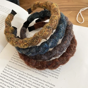 Close-up of three knitted acrylic wavy headbands in yellow, blue and brown tones