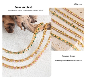 Macro detail of gold beaded tassel necklace with green and pink enamel pendants