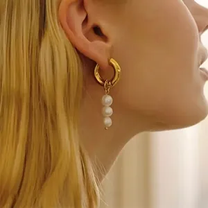 Detail of baroque freshwater pearl drop earrings with polished gold hoop on female model
