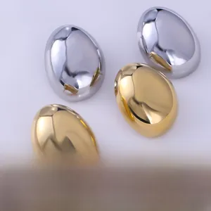 Polished liquid metal oval studs in gold and silver finishes on a white tray