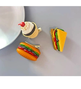 Close-up of realistic 3D food hair clips featuring a cupcake, hotdog, and sandwich
