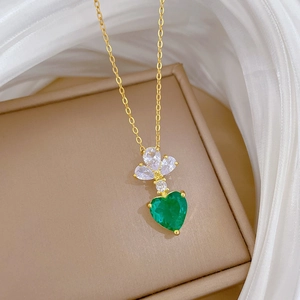 Elegant gold necklace with green heart gemstone on silk fabric for a luxury aesthetic