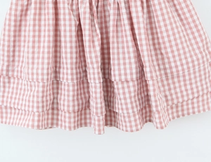 Gros plan sur le tissu vichy rose et blanc avec volants étagés sur une mini-jupe