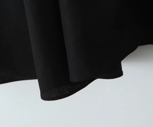 Close-up of black pleated dress hem showing fabric texture and neat stitching details