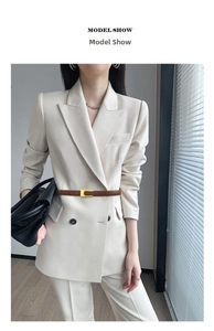 Close-up of a slim brown leather belt with a gold buckle on a cream blazer suit