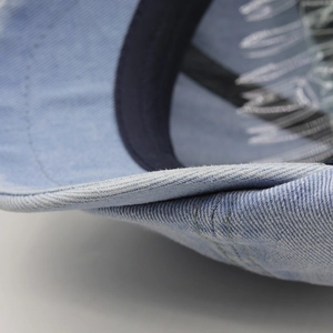 Close-up detail of light blue washed denim cap brim with reinforced double stitching