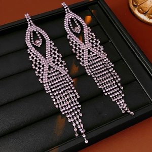Macro shot of long drop earrings with pink rhinestones displayed on a black jewelry box