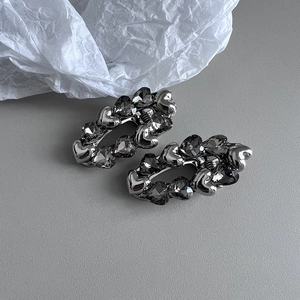 Detail of two silver metal hair clips with dark crystals in a heart design