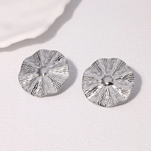 Détail de boucles d'oreilles argentées avec plis radiaux et finition brillante