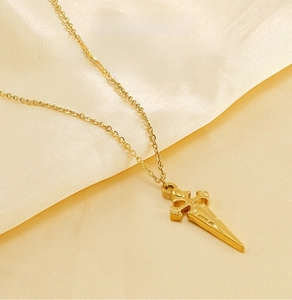 Close-up of golden stainless steel cross pendant on smooth cream silk fabric background