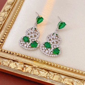 Macro detail of silver gourd earrings set with green stones, zircons, and pearls