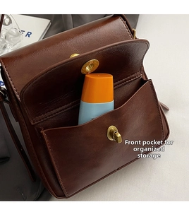 Detail view of the deep brown oil wax leather shoulder bag featuring a functional front pocket