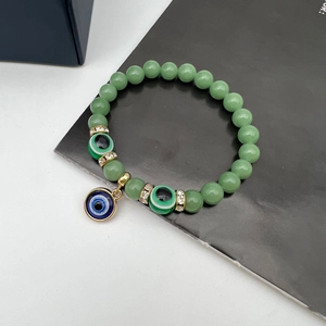 Close-up of green beads and evil eye charms on a bohemian stretch bracelet detail