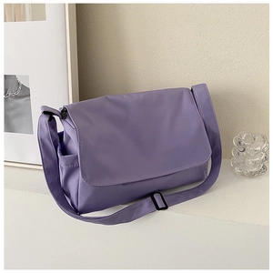 Detail view of the purple nylon messenger bag with adjustable shoulder strap on a white stand