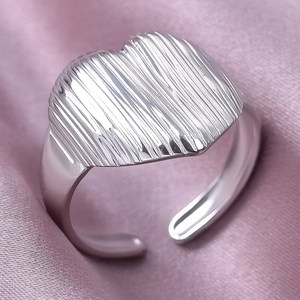 Vue macro d'une bague coeur argentée avec texture verticale et anneau ouvert réglable