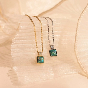 Detailed macro view of square opal pendants in gold and silver on silk background