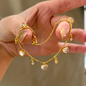 Close-up of heart tassel bracelet with transparent beads worn on a model's wrist