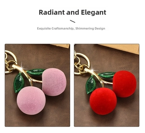 Close-up of pink and red flocked cherry keychains with green leaves and gold hardware