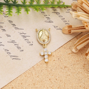 Detailed close-up of 18K gold-plated Mary pendant with cross on vintage paper