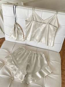 Three-piece satin pajama set with V-neck camisole, ruffled shorts, and matching drawstring bag