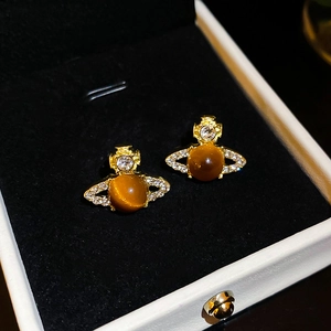 Detail of Saturn orb earrings with sparkling rhinestones and a brown cat-eye stone