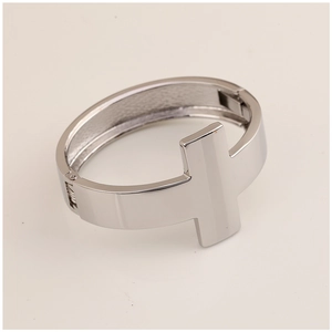 Detailed close-up of a silver polished metal cuff featuring an overlapping T-bar design