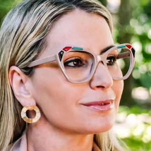 Detail of retro cat-eye sunglasses with colorful blocks and brushed gold earrings