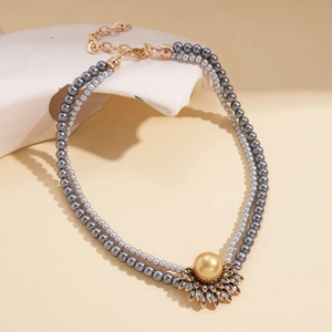 Dettaglio collana di perle grigie a doppio filo con ciondolo a girasole dorato