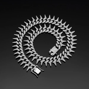 Macro detail of silver spiked Cuban link necklace with sparkling crystals on black surface
