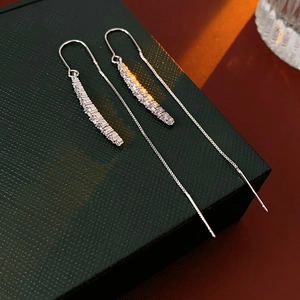 Orecchini a nappa con catena in argento e zirconi su una confezione regalo verde scuro