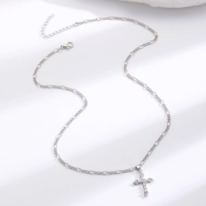 Detail of silver Figaro chain necklace with clear cubic zirconia cross pendant and lobster clasp